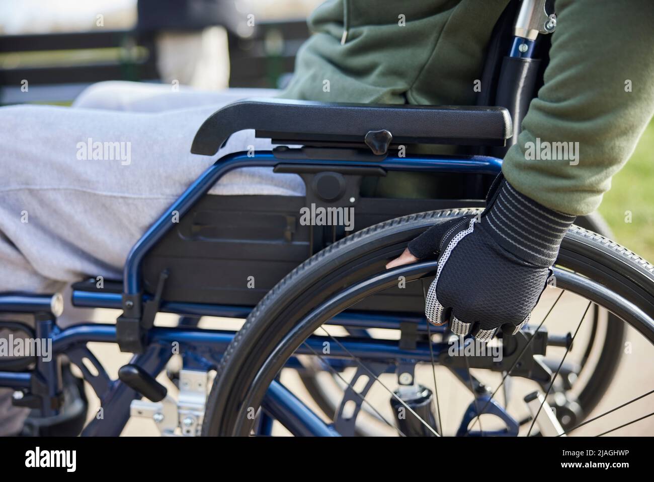 Primo piano di Teenage Boy indossando guanti protettivi in sedia a rotelle a Park Foto Stock