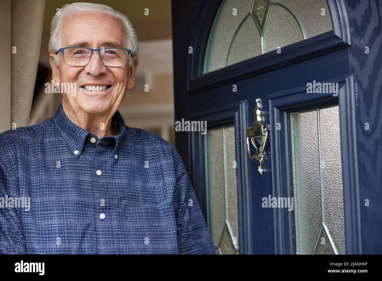Ritratto di sorridente uomo anziano in piedi alla porta aperta della casa Foto Stock