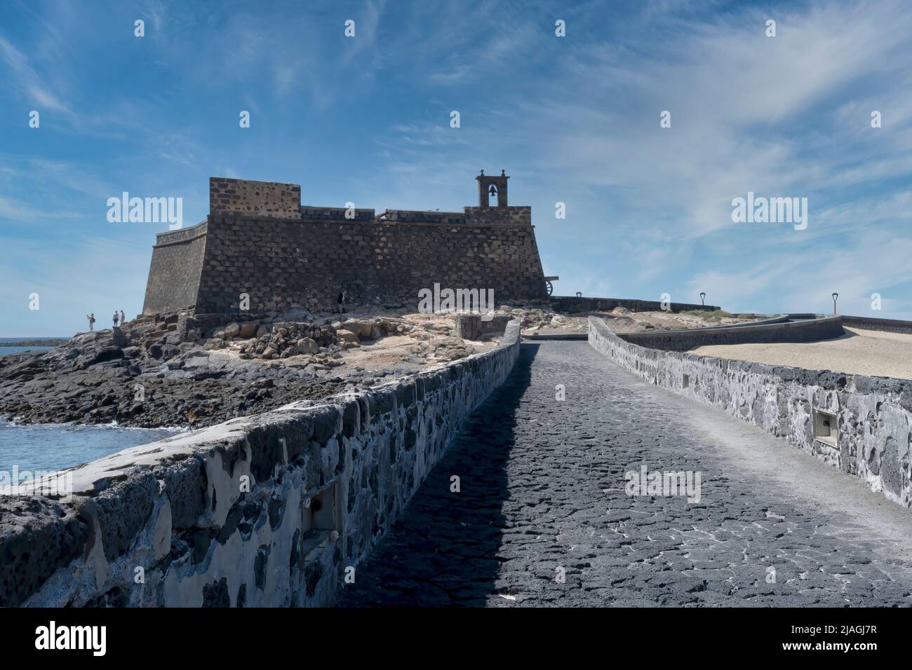 Vista lungo la strada rialzata in pietra per Castillo San José, ad Arrecife, Lanzarote, Isole Canarie. Il castello si affaccia su Puerto Naos. Foto Stock