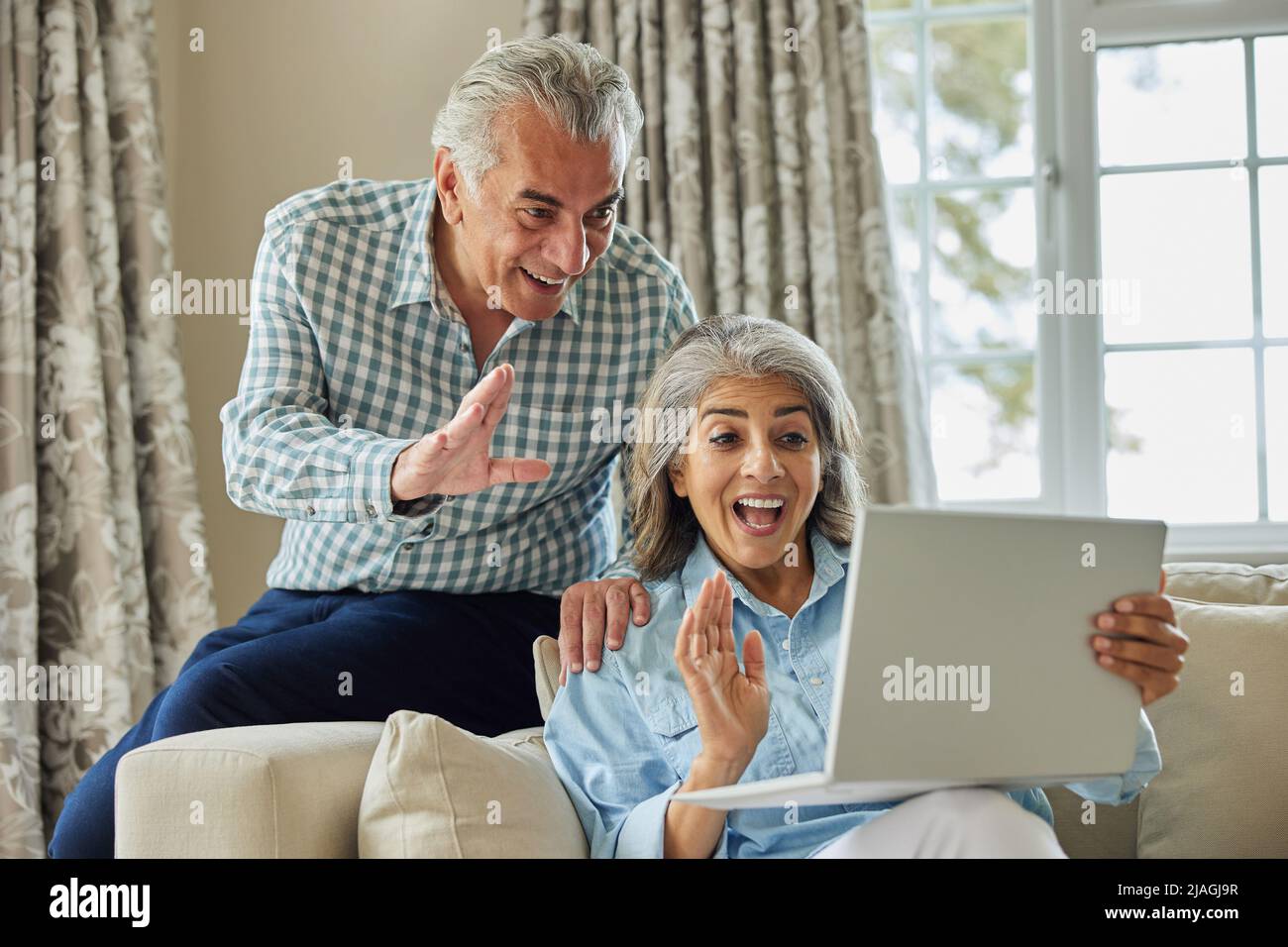 Coppia matura a casa che ha una chat video con la famiglia Foto Stock