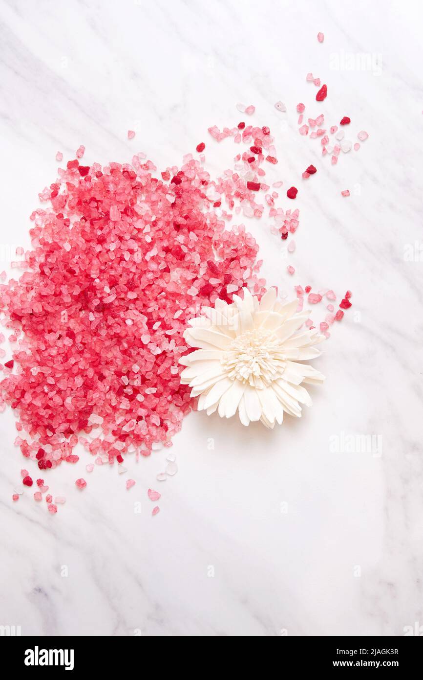 Sale da bagno rosa sparso sul tavolo di marmo in un salone spa con fiori. Assistenza sanitaria e medicina alternativa Foto Stock