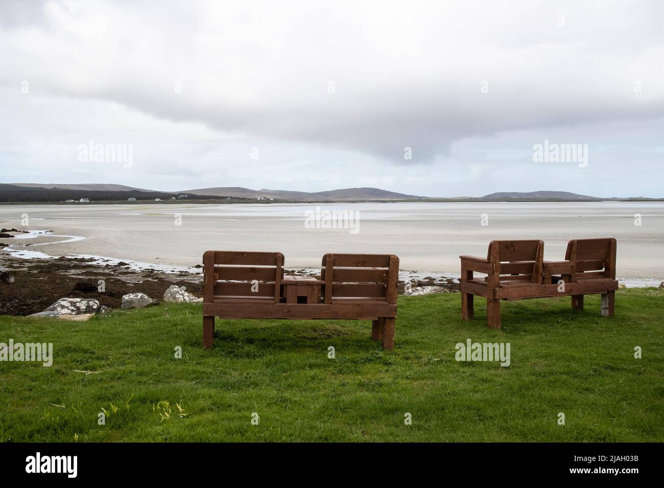 Panchine pubbliche in legno che forniscono posti a sedere per residenti e visitatori che si affacciano su Vallay Sands a North Uist nelle Isole Ebridi esterne Scozzesi Foto Stock