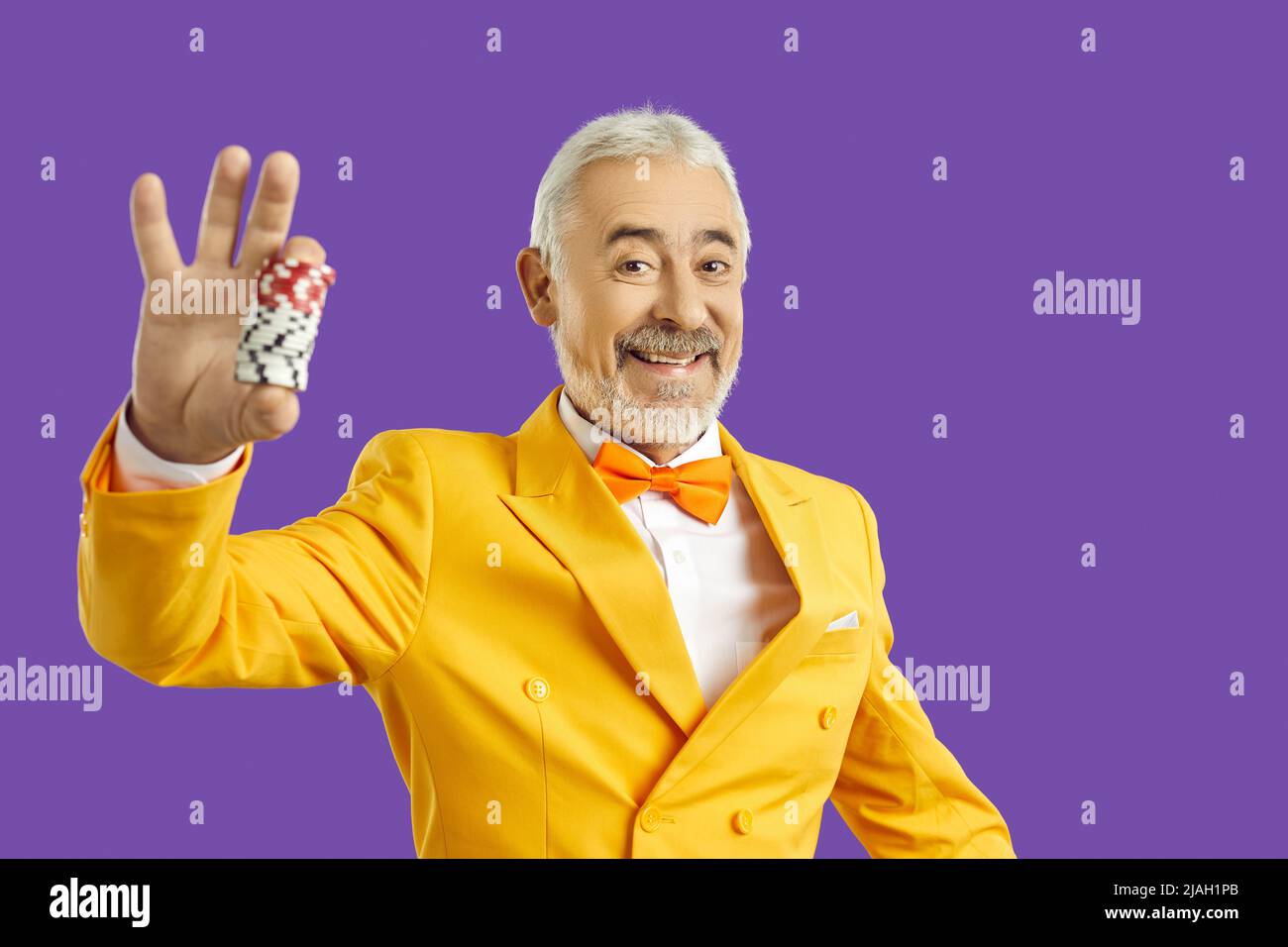 Uomo anziano sorridente con chip da casinò in mano Foto Stock