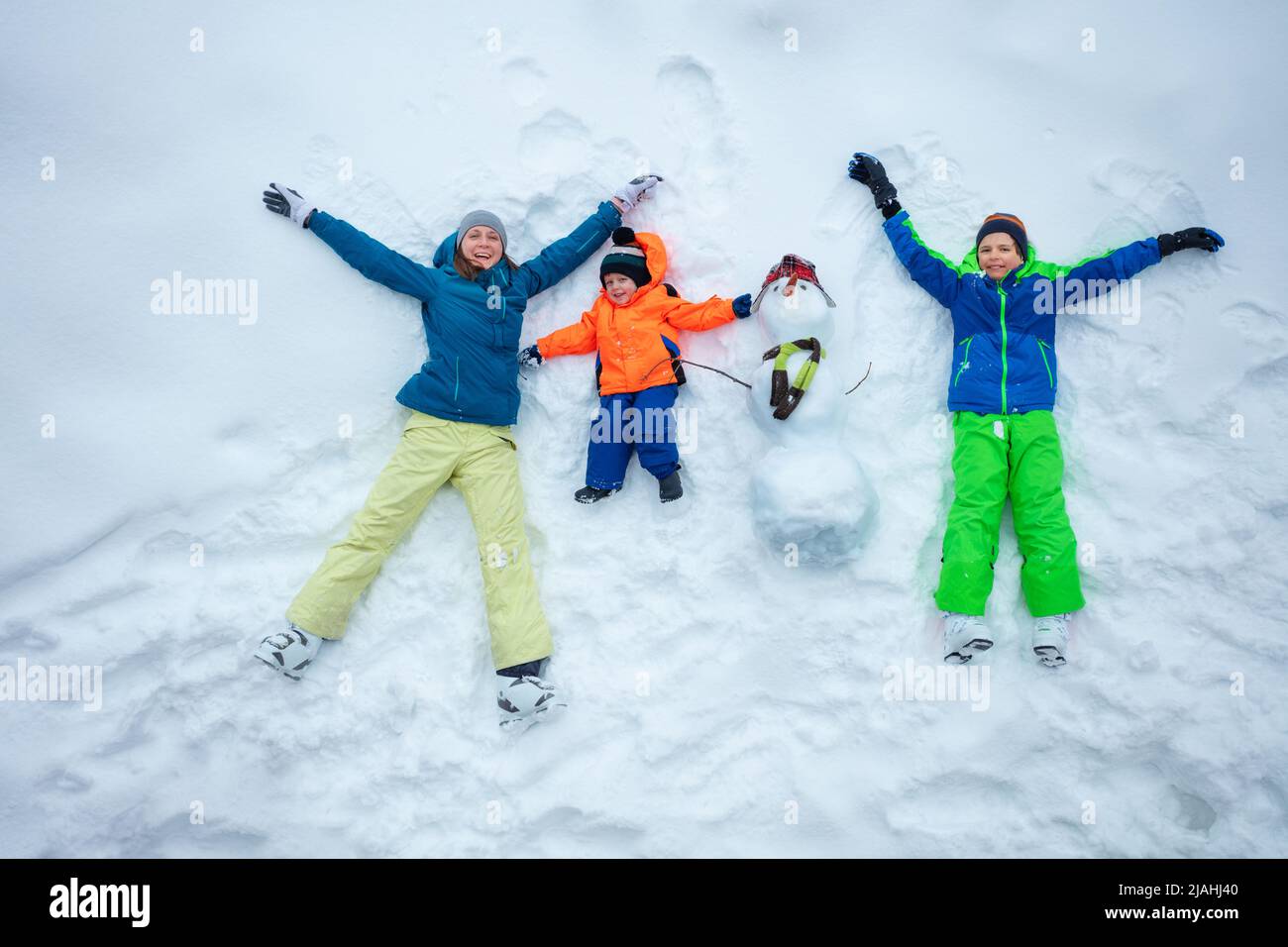 Madre e due ragazzi si posano sulla neve con vista dall'alto Foto Stock