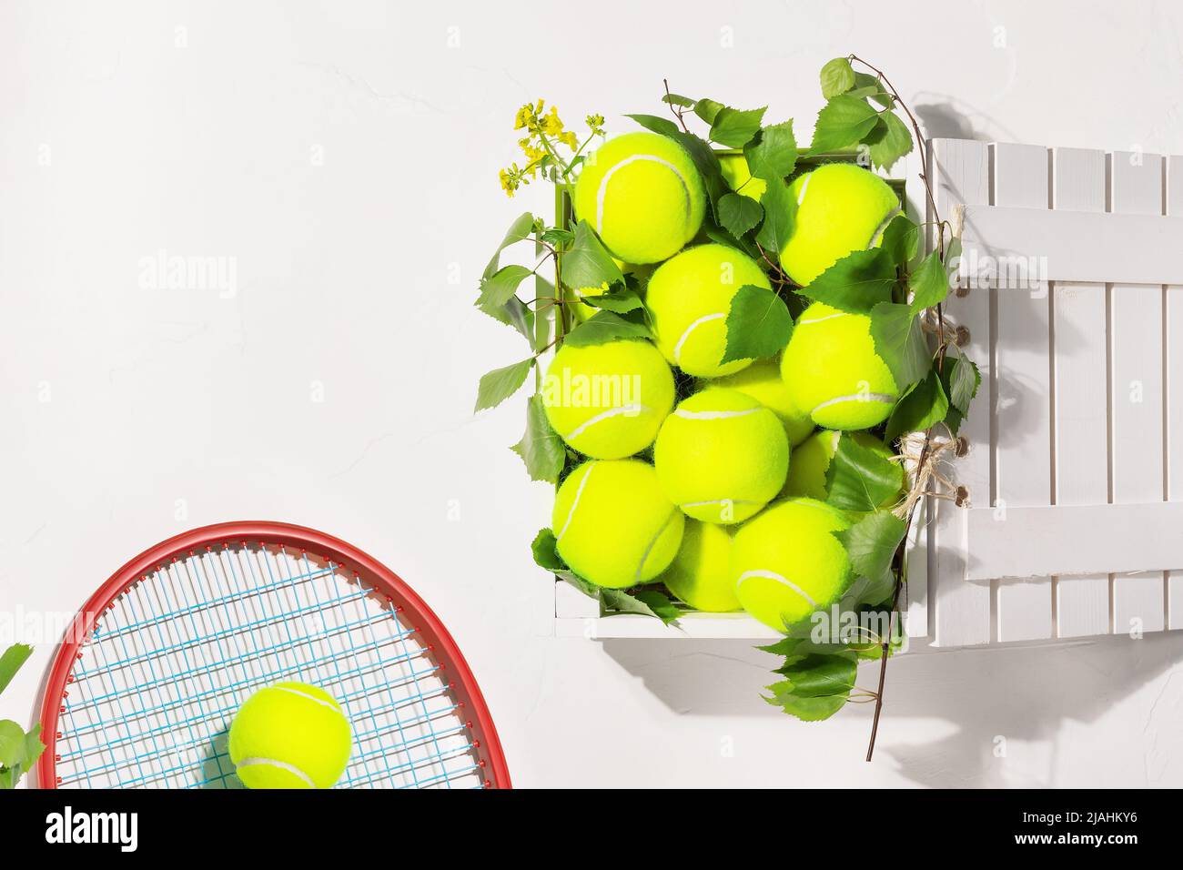 Palline da tennis in una scatola di legno e racket su sfondo bianco Foto Stock