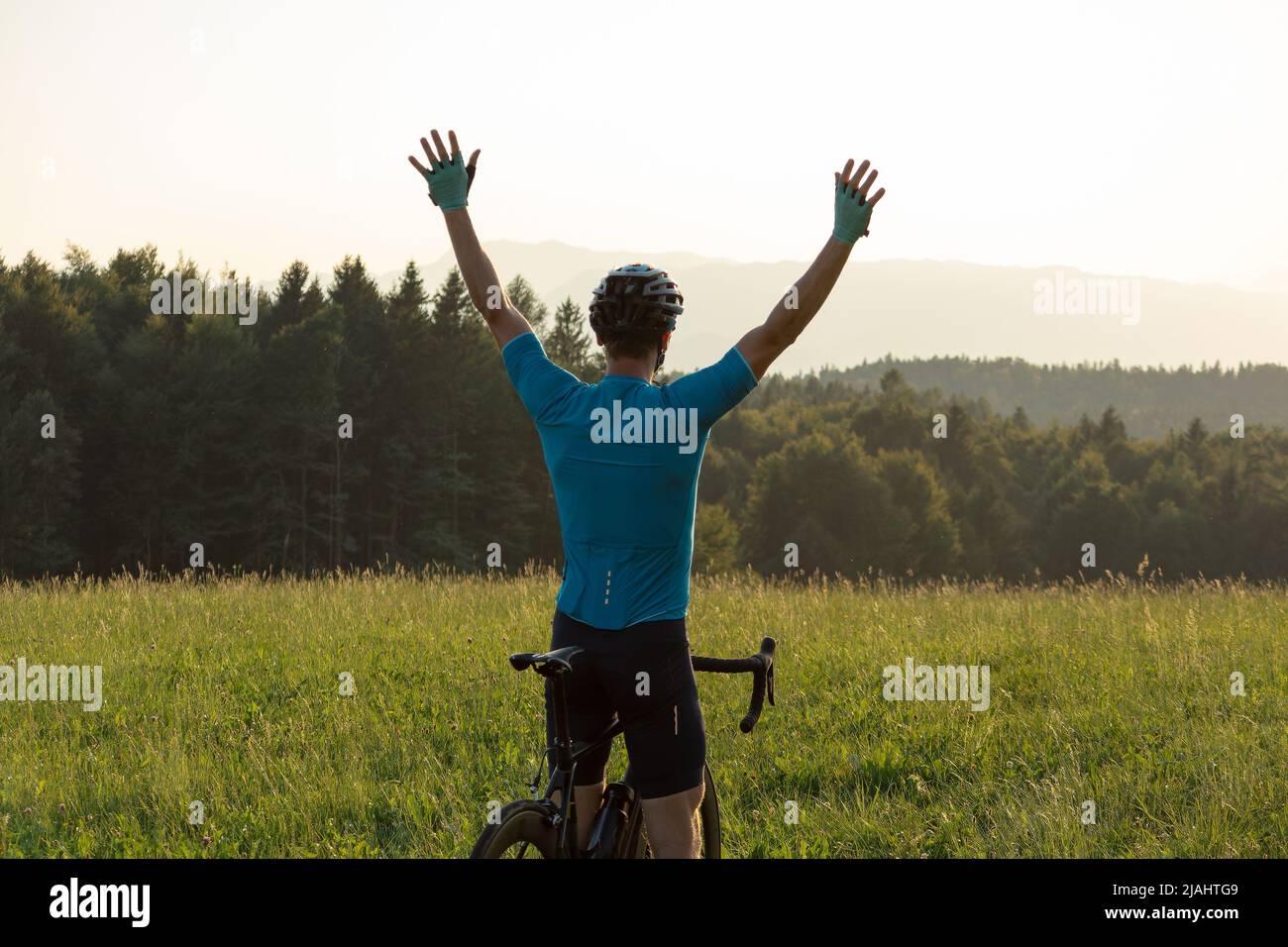 Atleta maschile professionista da corsa in bicicletta con le braccia sollevate sopra la testa, in una posizione di vittoria Foto Stock