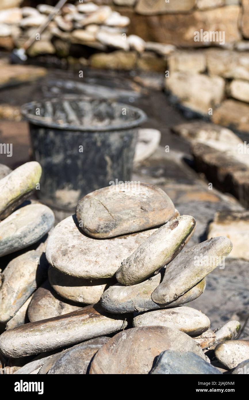 Grandi pietre sporche sullo sfondo della piscina. Costruzione e pulizia di un laghetto ornamentale nel giardino. Disegno paesaggistico. Foto Stock