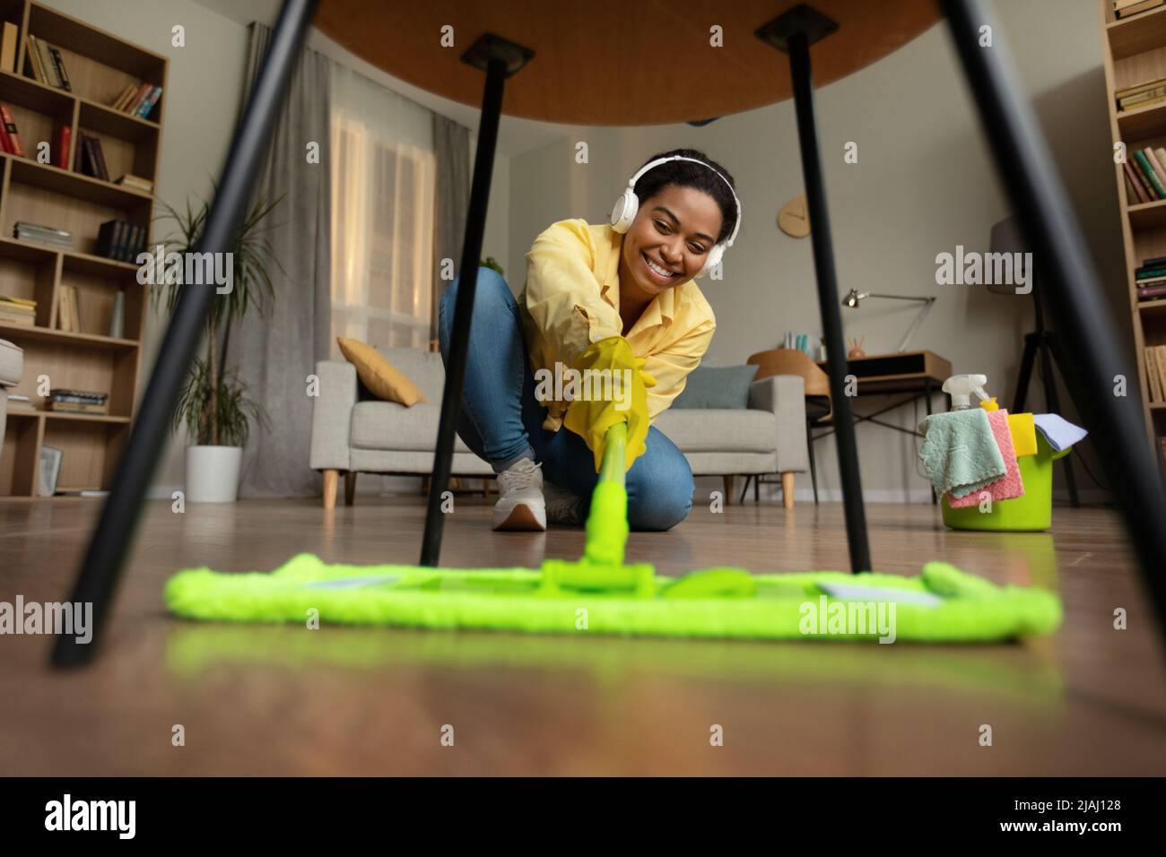 Happy African American Lady Mopping Floor Cleaning Room in Home Foto Stock