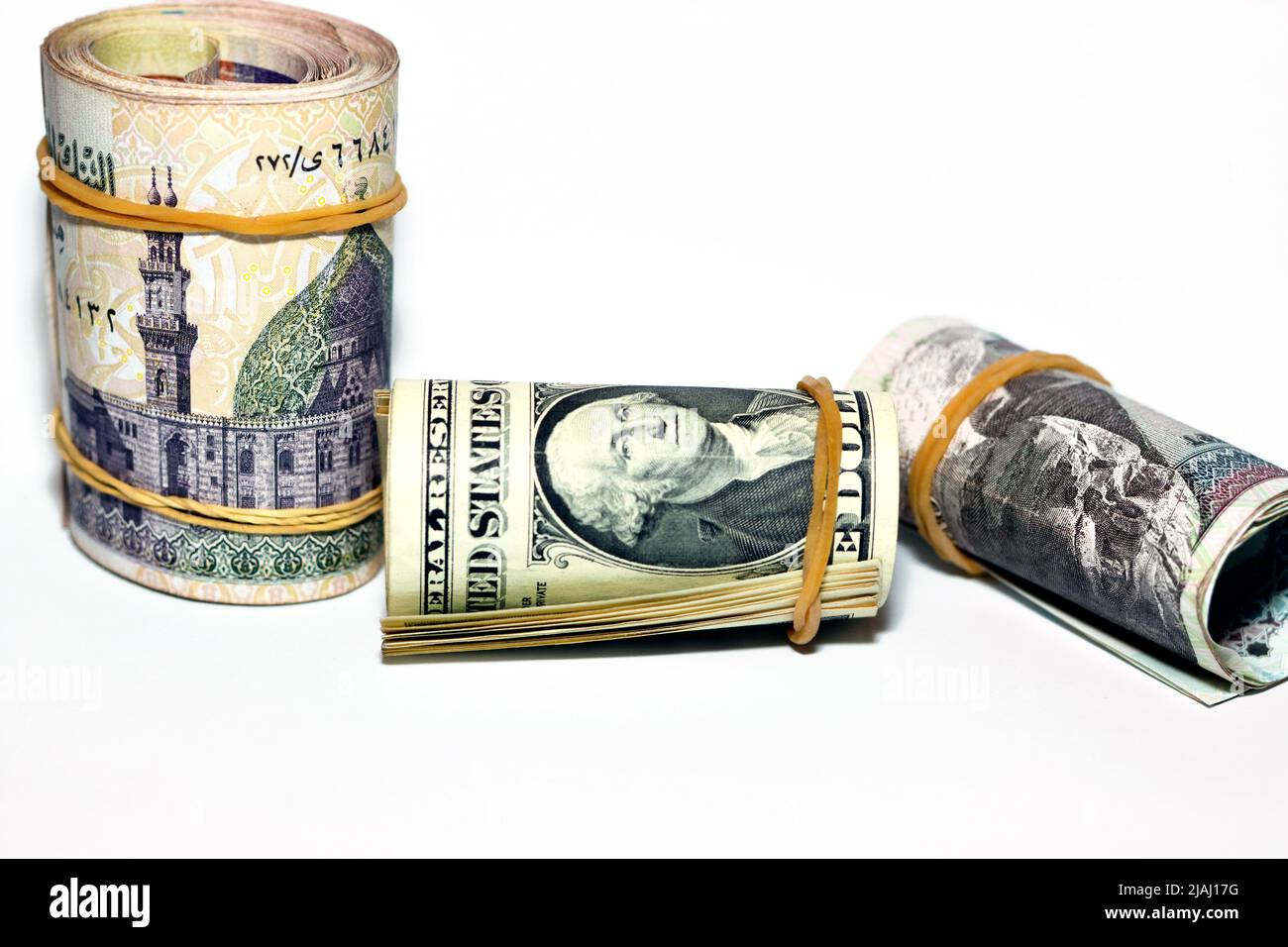 Fuoco selettivo di un mucchio di rotoli di dollari americani con arrotolati banconote in denaro egiziano di 100 LE, 200 LE cento duecento sterline, Foto Stock