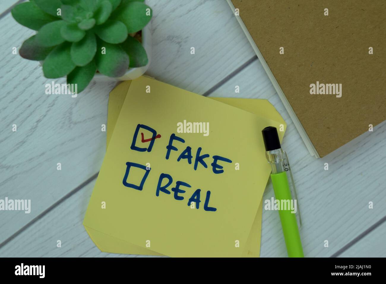 Concetto di falso o reale? Fake scrivere su note appiccicose isolato su tavola di legno. Foto Stock