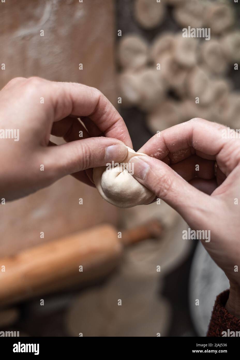 Una donna in cucina scolpisce gnocchi di pasta con ripieno di carne. Cucina deliziosi gnocchi fatti in casa. Foto Stock