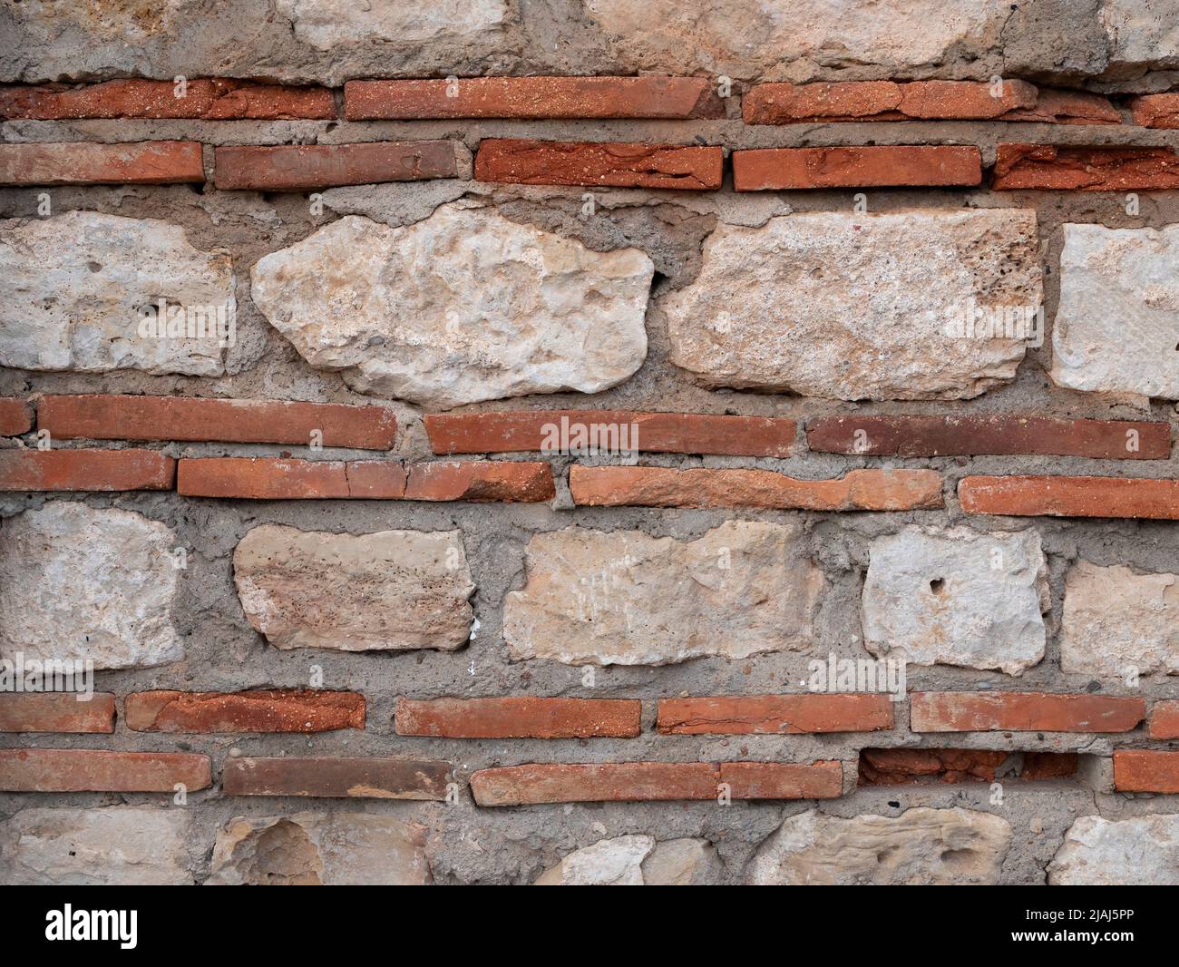 Struttura di muratura in mattoni e pietra. Sfondo di un vecchio muro. Combinazione di plinti, mattone sottile speciale e calcare come materiali da costruzione i Foto Stock
