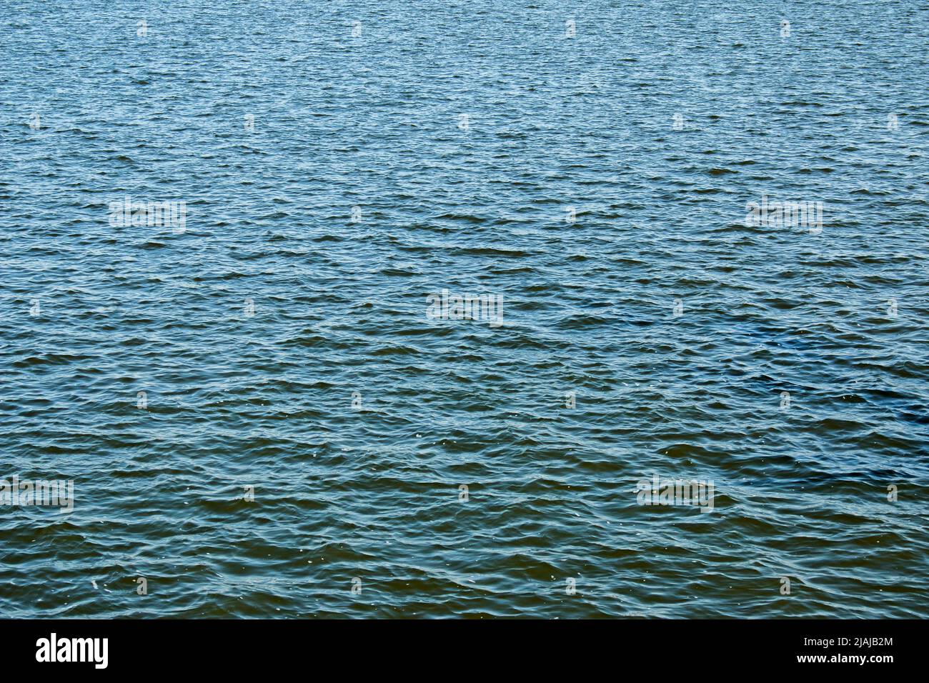 Calmo superficie d'acqua con piccole increspature. Sfondo della superficie dell'acqua del fiume in una giornata di sole. Foto Stock
