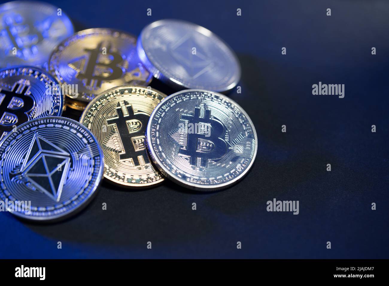 Monete Bitcoin sotto la luce blu. Sfondo nero Foto Stock