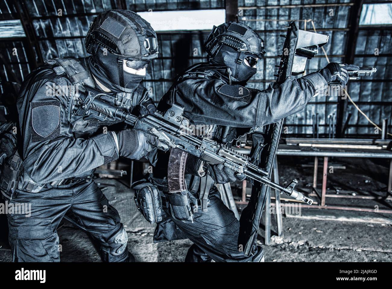 La squadra di reazione speciale della polizia punta le pistole mentre si muove in avanti sotto la copertura dello scudo balistico su un raid. Foto Stock