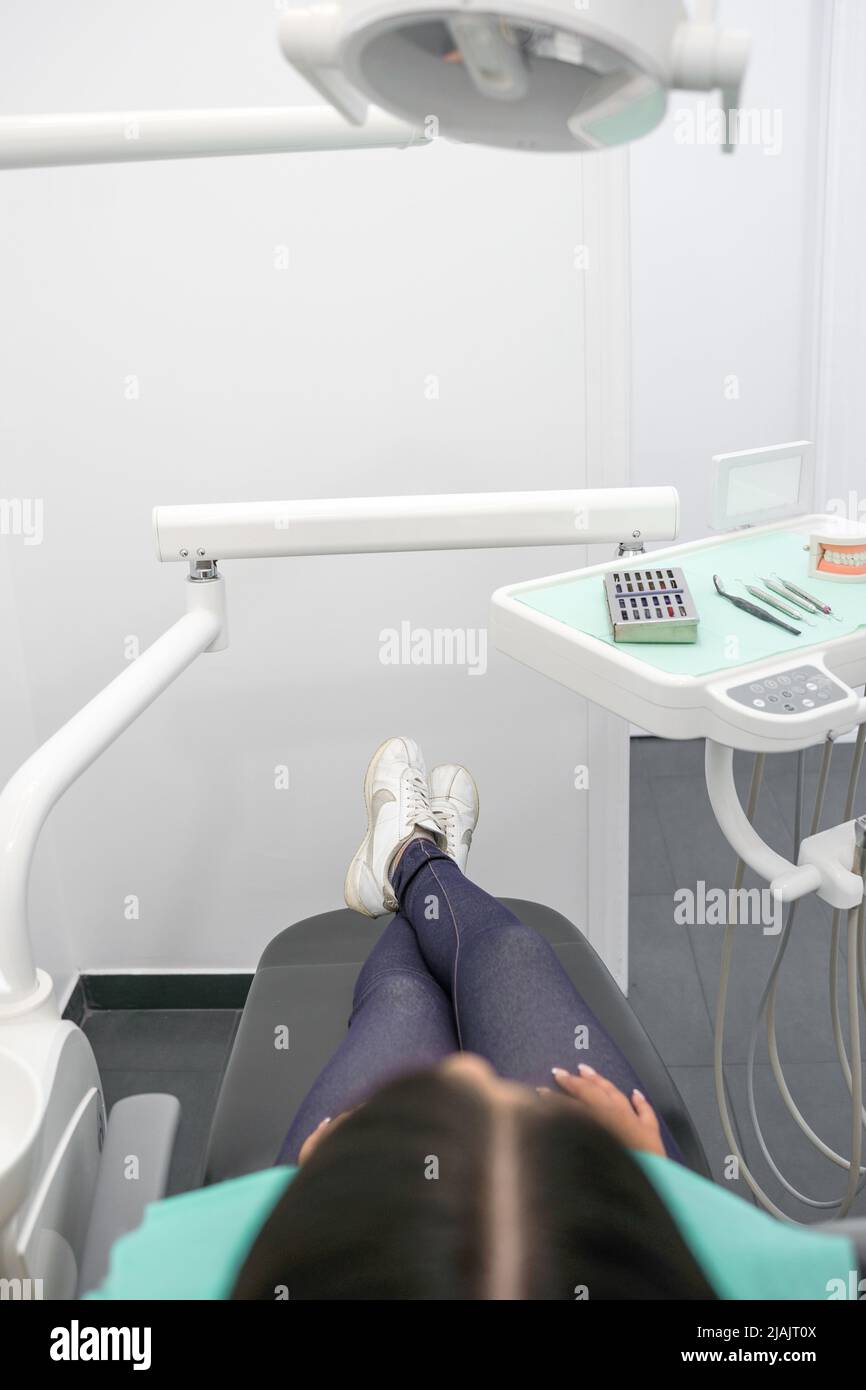 seduta sulla sedia reclinabile di un ufficio dentale in attesa di essere frequentato, medicina e strumenti medici, prevenzione e salute Foto Stock