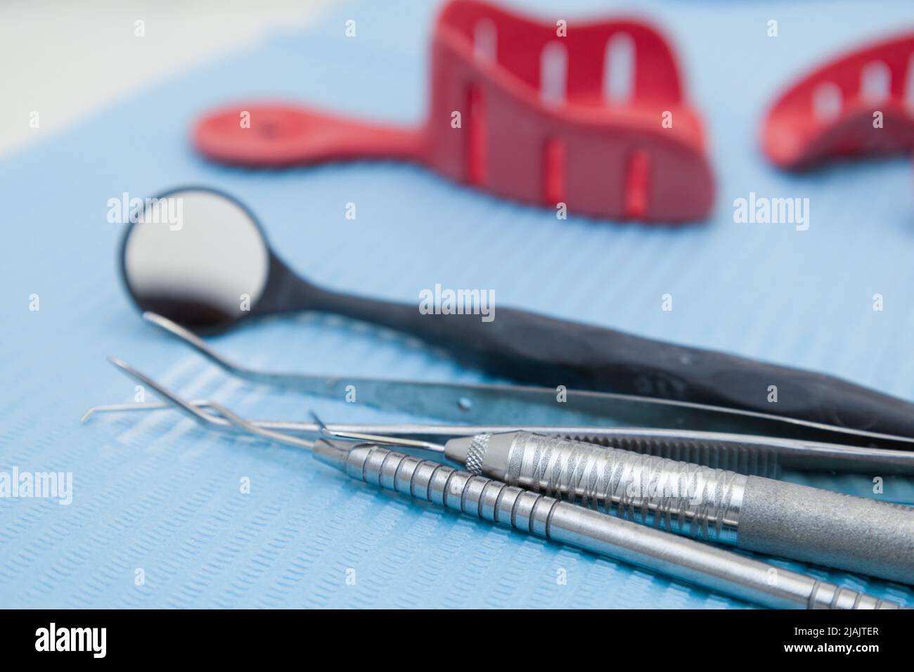 dettaglio delle pinzette e dello specchio dentale sterile sul tavolo da lavoro, strumenti medici pronti per l'uso in ufficio, oggetti metallici, studio Foto Stock