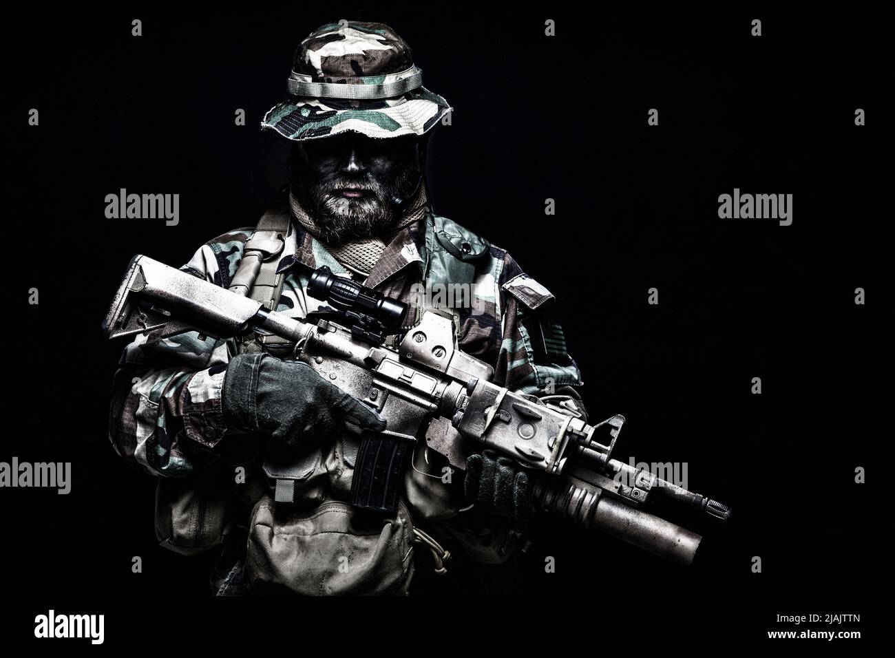 Commando soldato in divisa da battaglia, cappello di boonie e vernice facciale, armato con un fucile d'assalto. Foto Stock