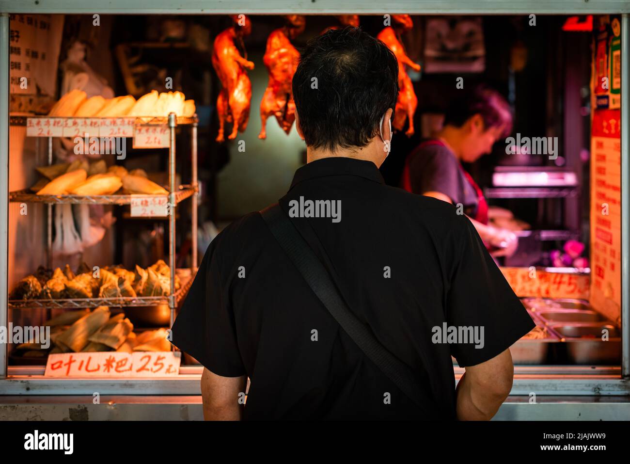 Uomo che acquista carne d'anatra in un negozio di strada in Cina Foto Stock