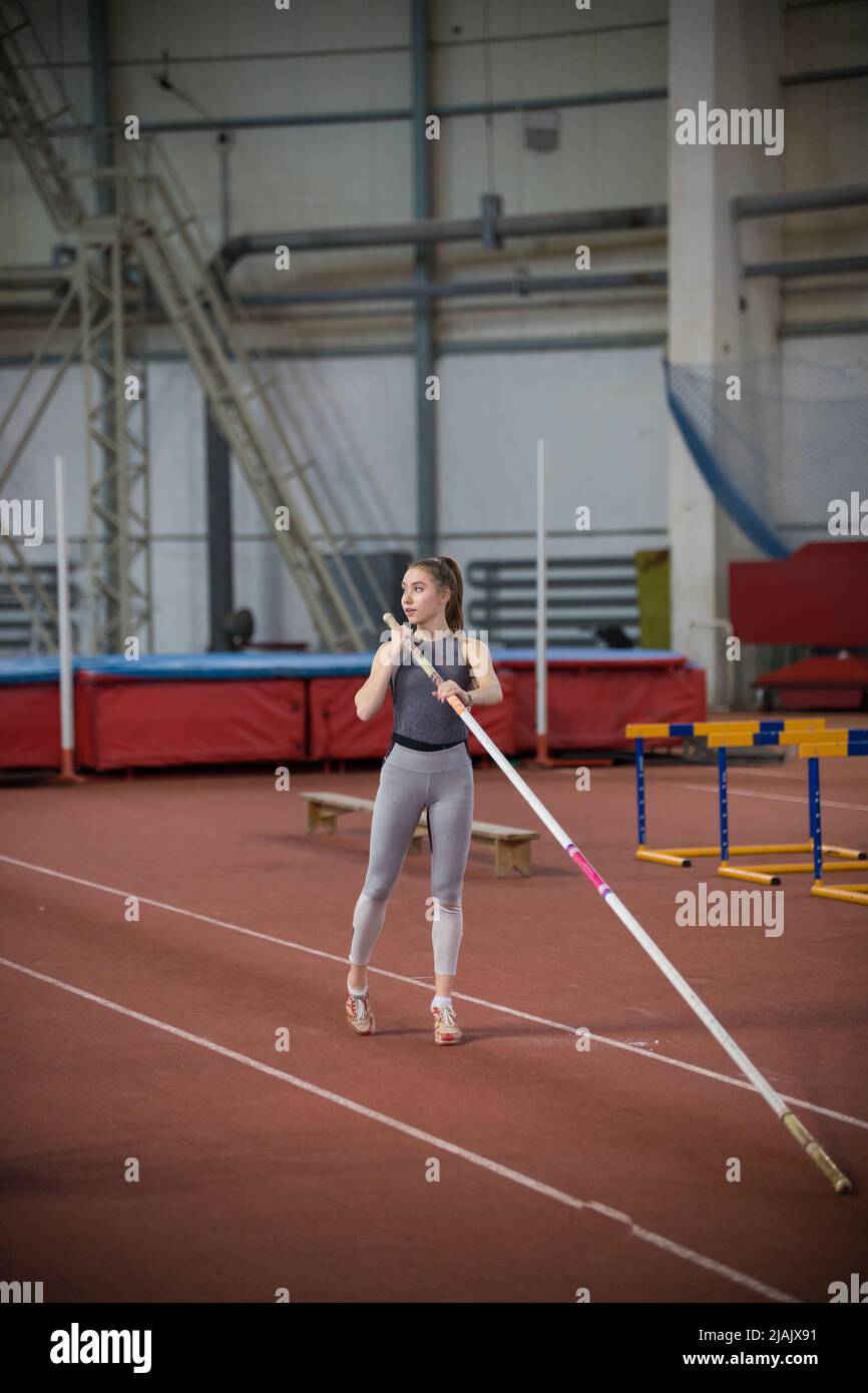 Palo che vaulting indoor - giovane bella donna in piedi sulla pista con un palo Foto Stock