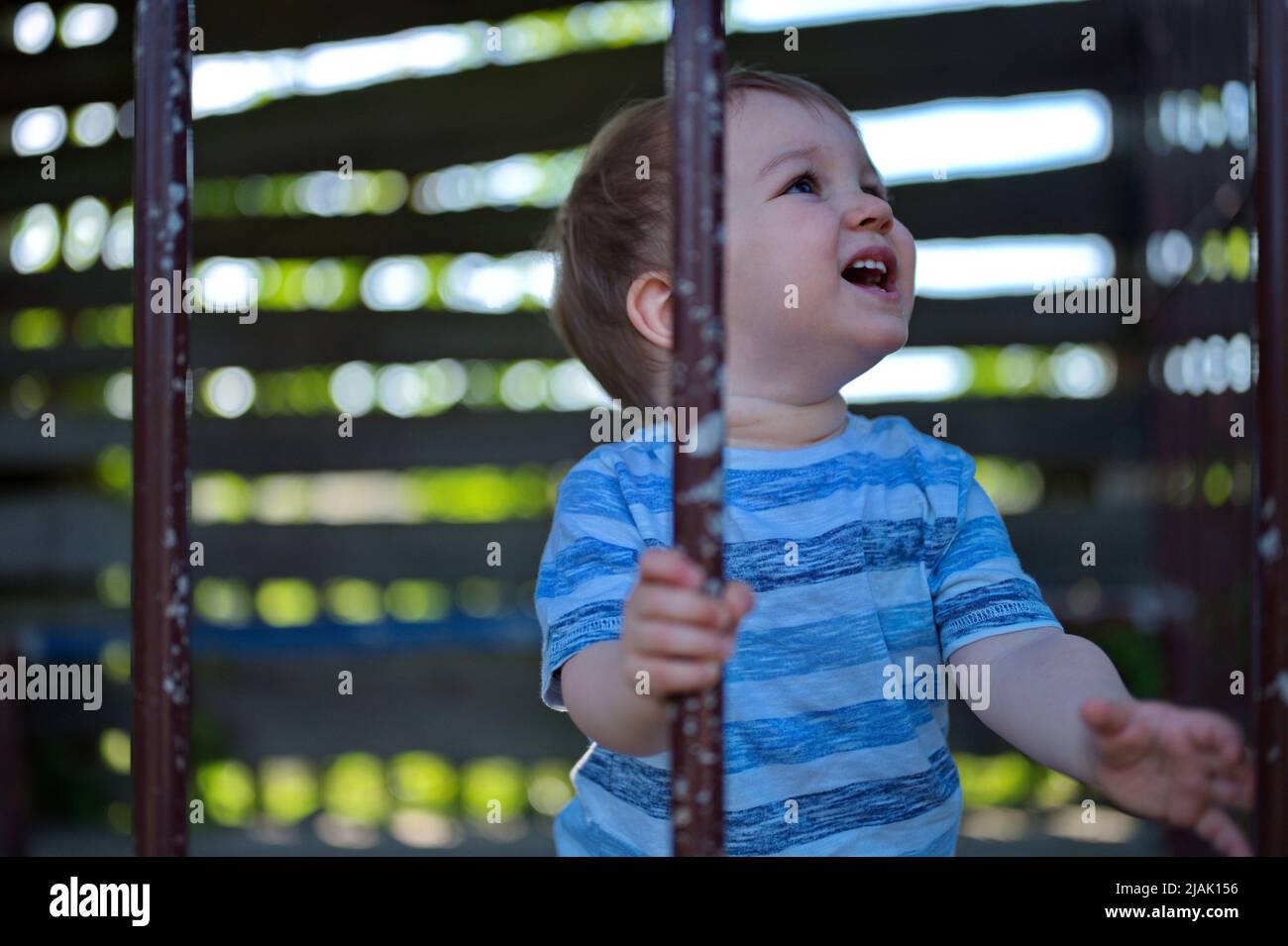 Carino ragazzino che tiene le barre della gabbia arrugginite Foto Stock