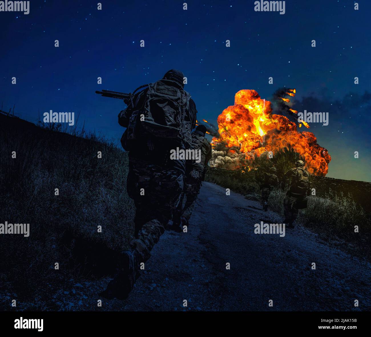 I soldati precipitano lungo una strada sterrata che attacca il nemico di notte, con una potente esplosione all'orizzonte. Foto Stock