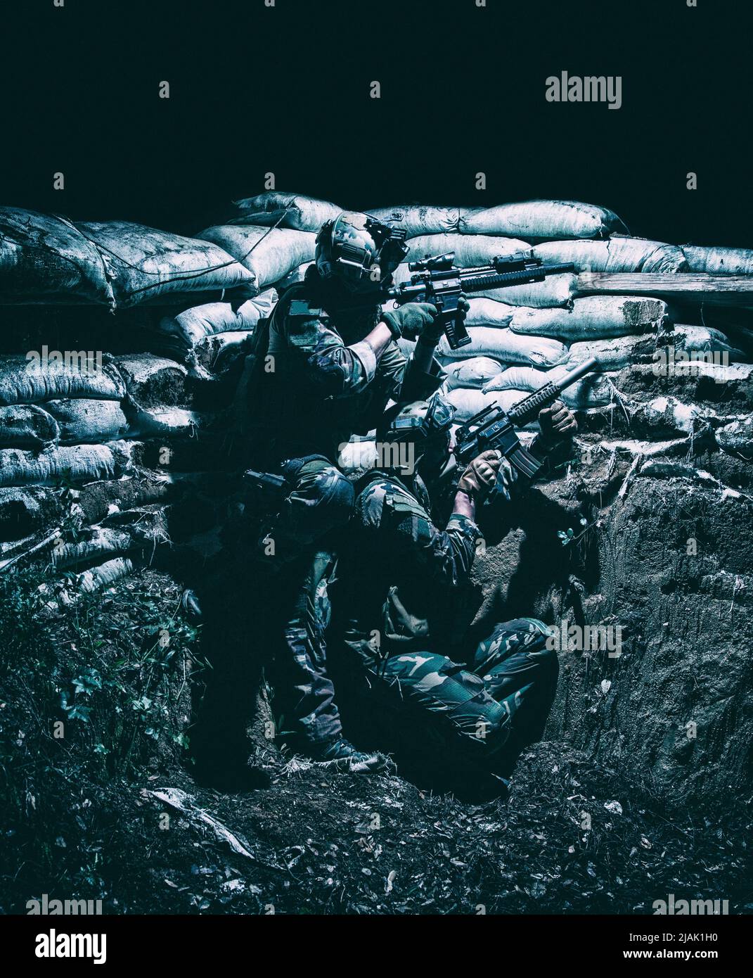 I soldati si coprono in una trincea dal fuoco nemico durante un attacco notturno. Foto Stock