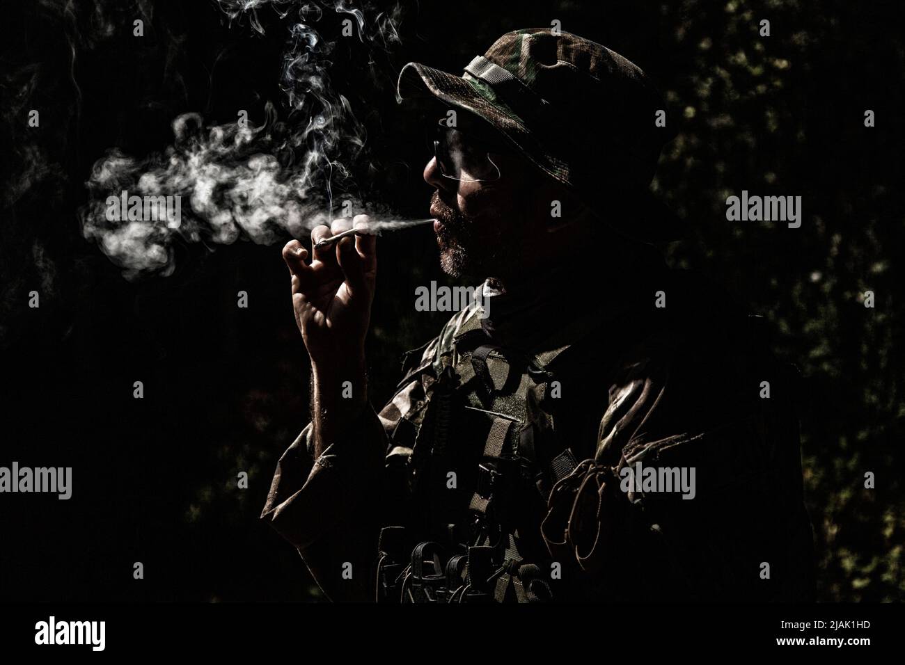 Il soldato dell'esercito fuma la sigaretta di notte. Foto Stock