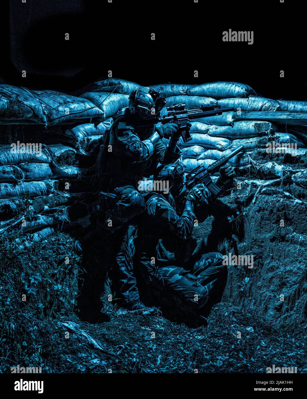 I soldati si coprono in una trincea dal fuoco nemico durante un attacco notturno. Foto Stock