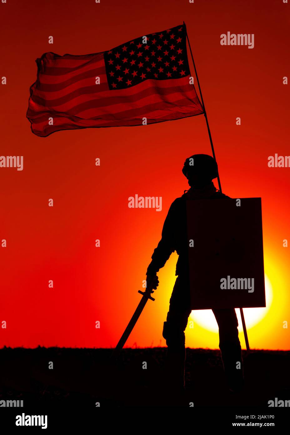 Silhouette di un soldato statunitense in piedi sotto la bandiera americana, armato di spada e scudo, con il sole che tramonta sullo sfondo. Foto Stock