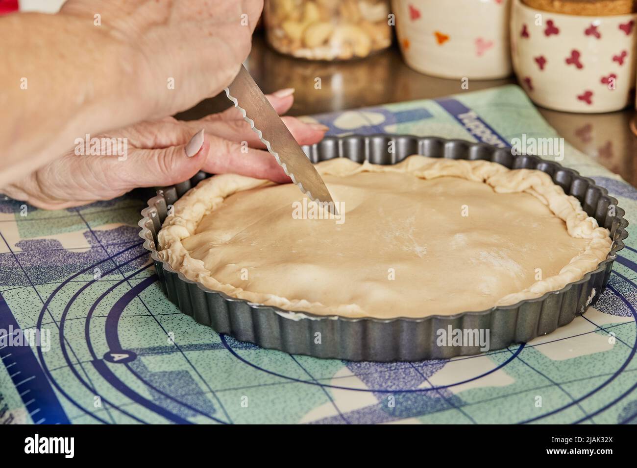 Lo chef prepara delle strisce sulla pasta per torte con il coltello prima di cuocere in forno Foto Stock