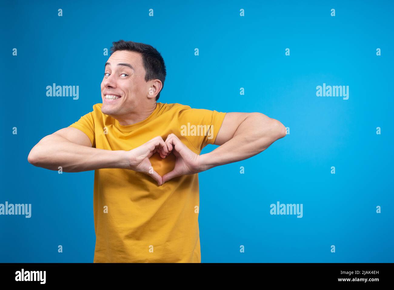 Uomo felice che mostra il gesto del cuore in studio Foto Stock
