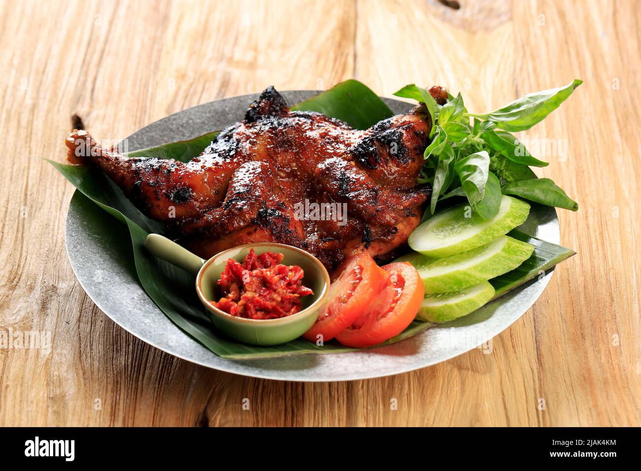 Pollo alla griglia con Lalapan, Bakakak Ayam Bakar con verdure fresche, ricetta autentica di pollo arrosto indonesiano. Su tavola di legno Foto Stock