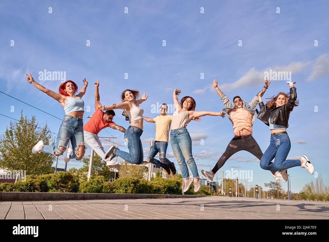 Gruppo di amici felici che sorridono alla fotocamera mentre saltano insieme all'aperto. Concetto di amicizia e felicità. Foto Stock