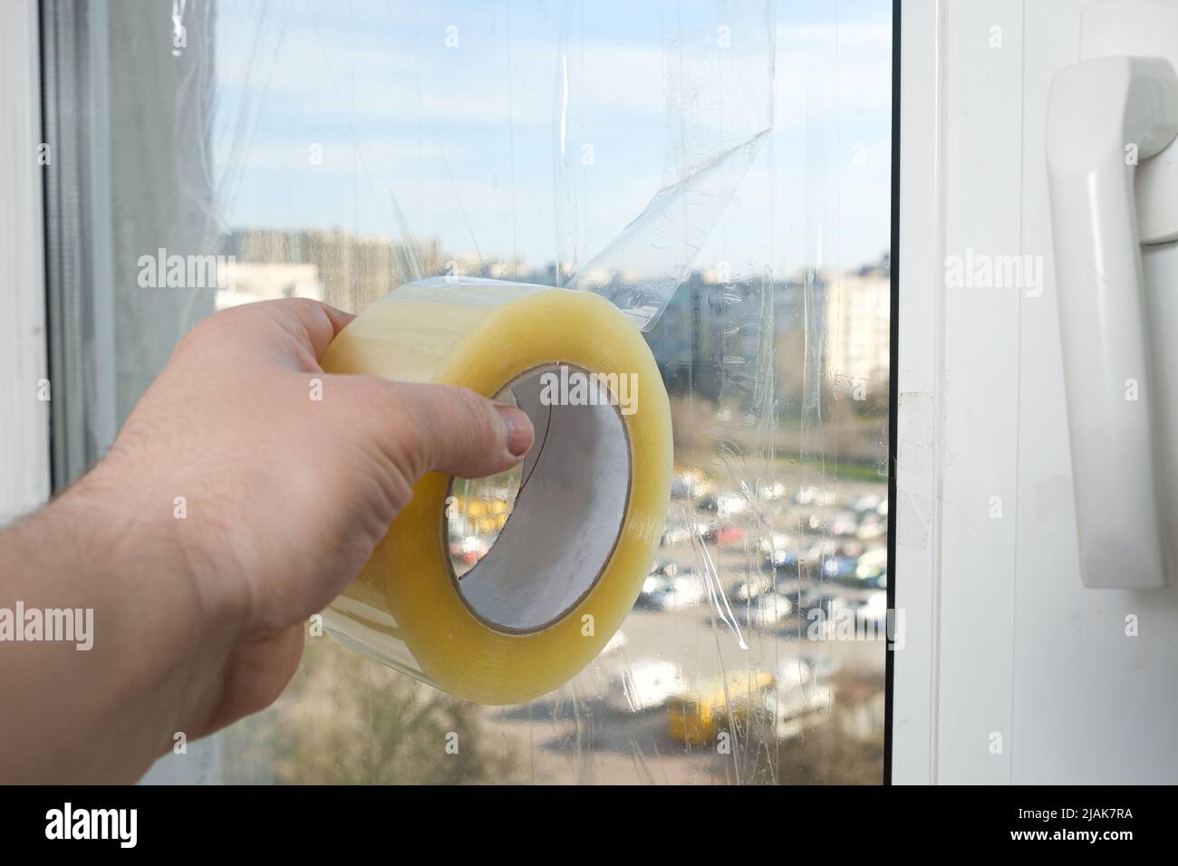 Sigillare le finestre con nastro adesivo durante la guerra in Ucraina per prevenire la formazione di molti frammenti durante l'ondata di esplosione Foto Stock