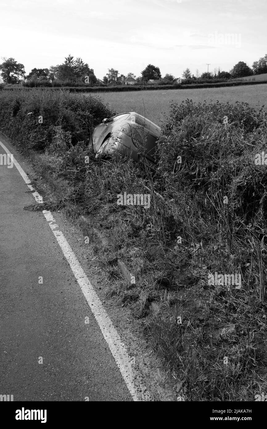 Maggio 2022 - Peugeot auto in un fosso accanto a una strada rurale prima cosa al mattino dopo un fine settimana Foto Stock