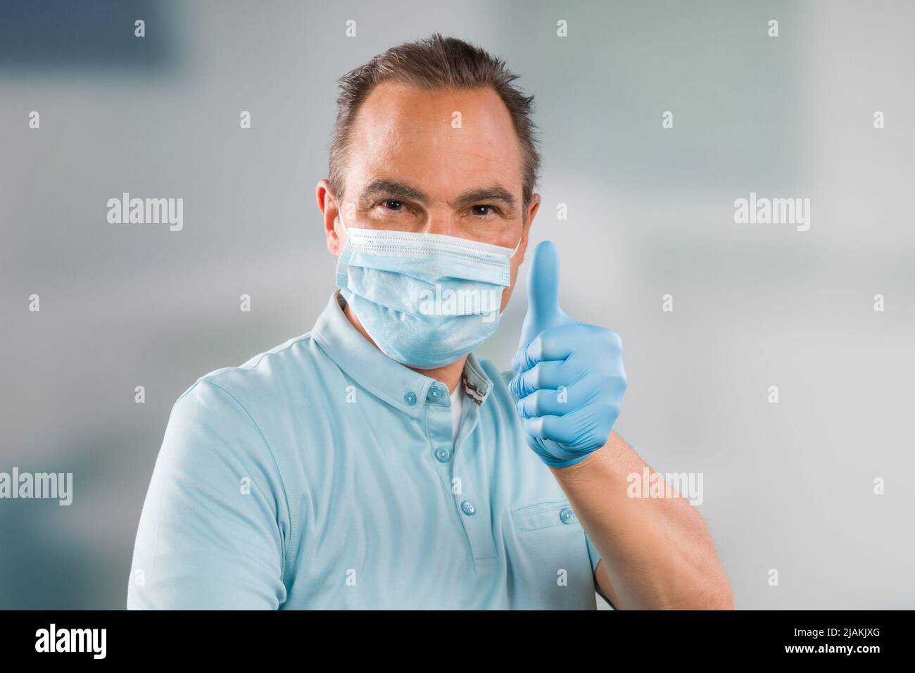 Medico con maschera medica e guanti medici mostra pollici-up Foto Stock