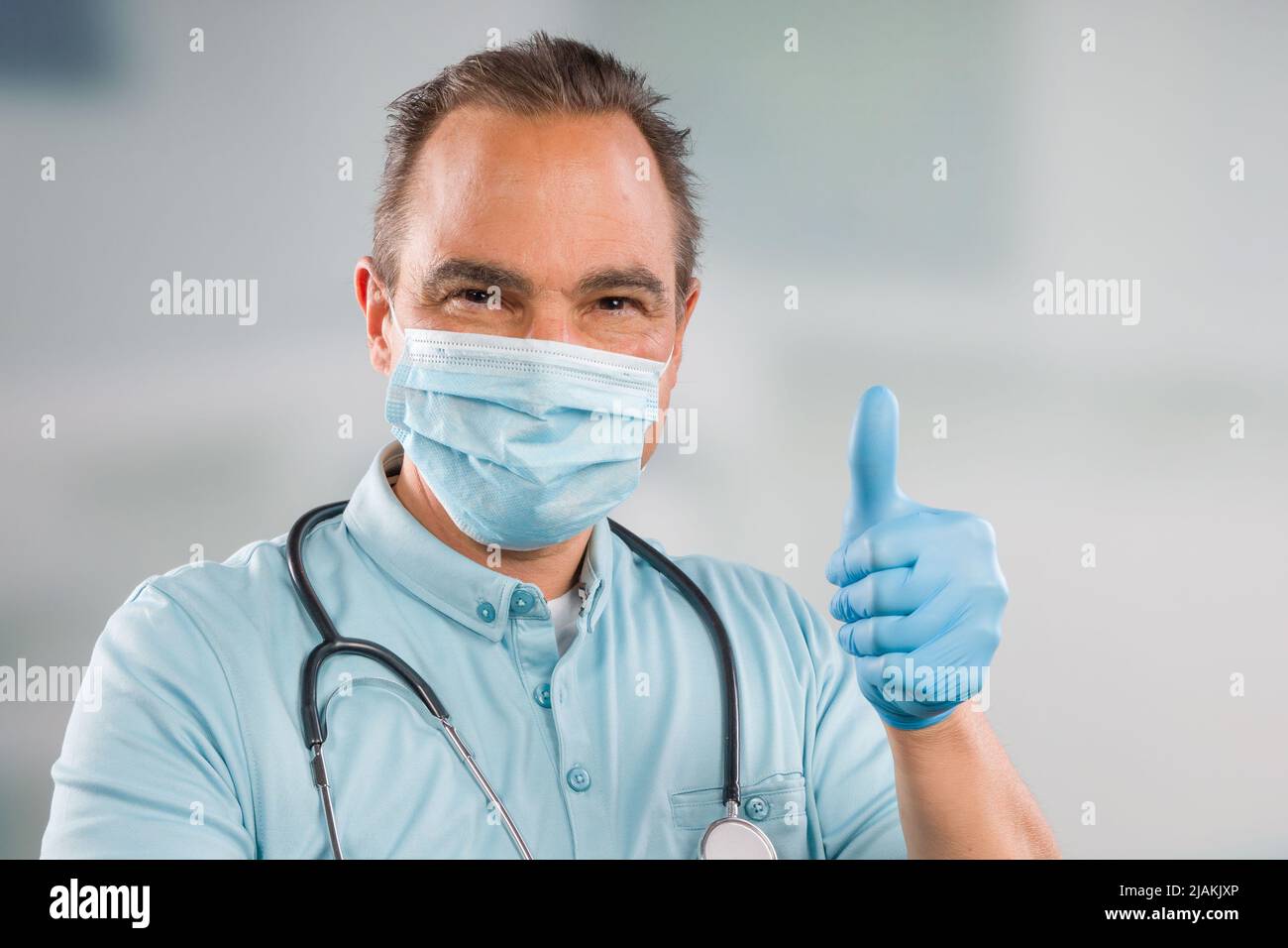 Medico con maschera medica e guanti medici mostra pollici-up Foto Stock