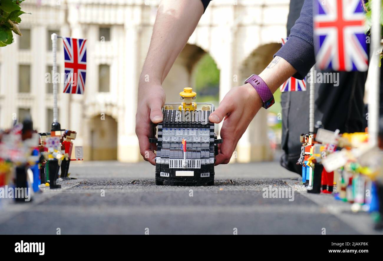 Model Maker Freya Groom colloca una replica della Regina Elisabetta II, riimmaginata in mattoni LEGO, in un veicolo animato come parte del Platinum Jubilee Display presentato oggi al LEGOLAND Windsor Resort. La regina animata e il veicolo ha preso 15hrs per costruire utilizzando 1.350 mattoni. LEGOLAND Windsor Resort ha presentato oggi i suoi modelli di ispirazione regale per celebrare il Giubileo del platino della Regina. Il numero complessivo di mattoni utilizzati è stato di 18.001 e i modelli hanno impiegato un totale di 281,5 ore per finire. Il display include anche una festa di strada e scena pic-nic, così come le versioni in miniatura dei reali, l'albero di Foto Stock