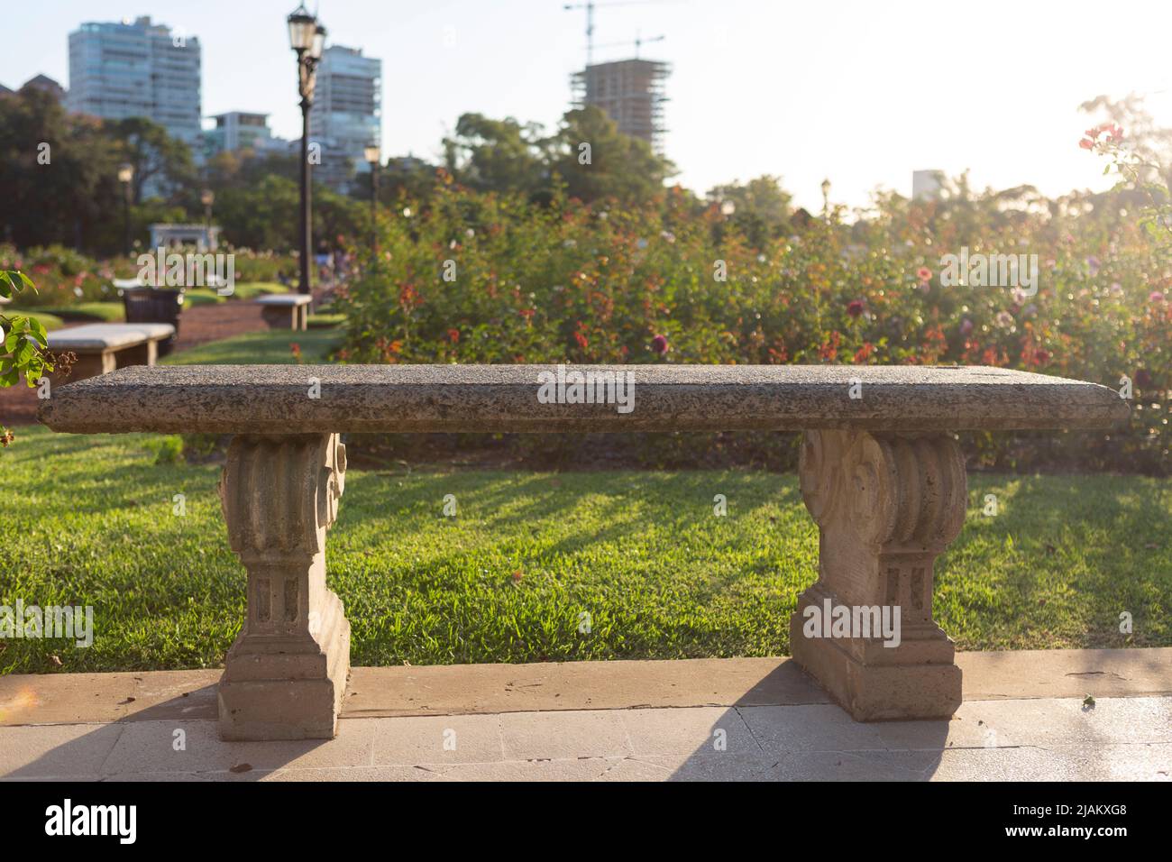 scena di panchina in pietra nel parco della città al tramonto Foto Stock