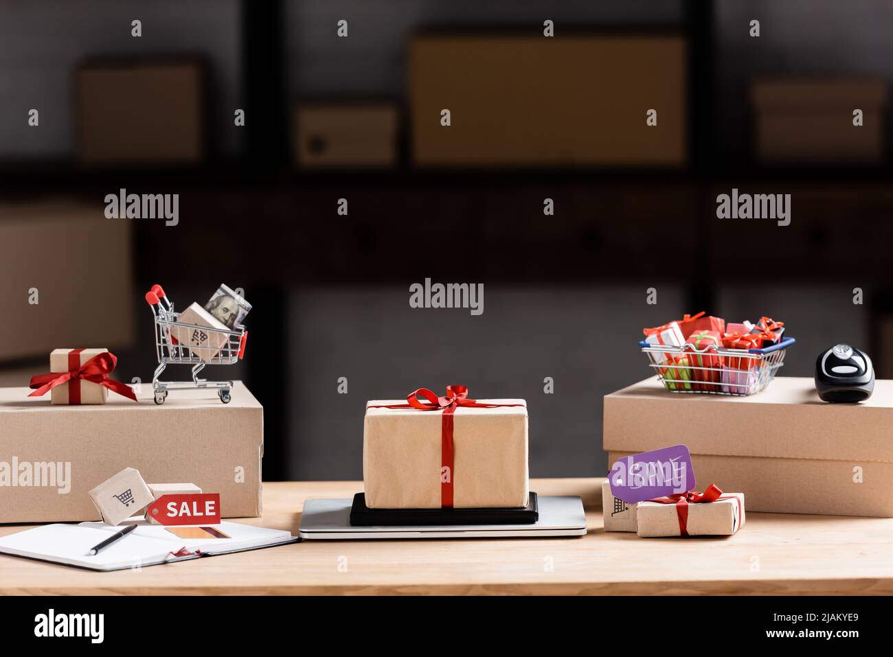 Scatole regalo, laptop e carrello giocattolo con denaro sul tavolo Foto Stock