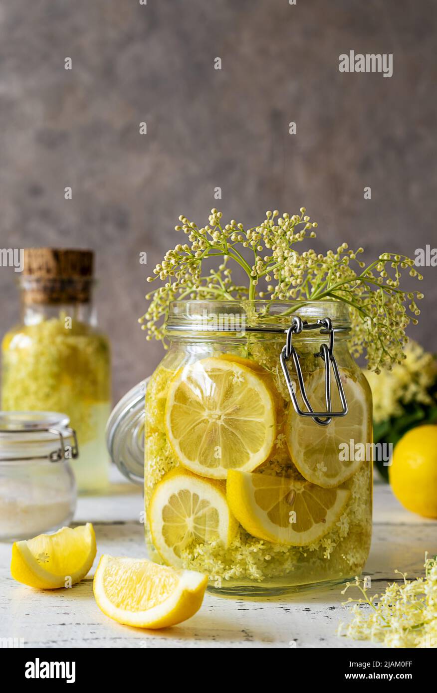 Acqua o sciroppo di sambuco fatti con fiori freschi e limoni come ingredienti di base. Sfondo grigio Foto Stock