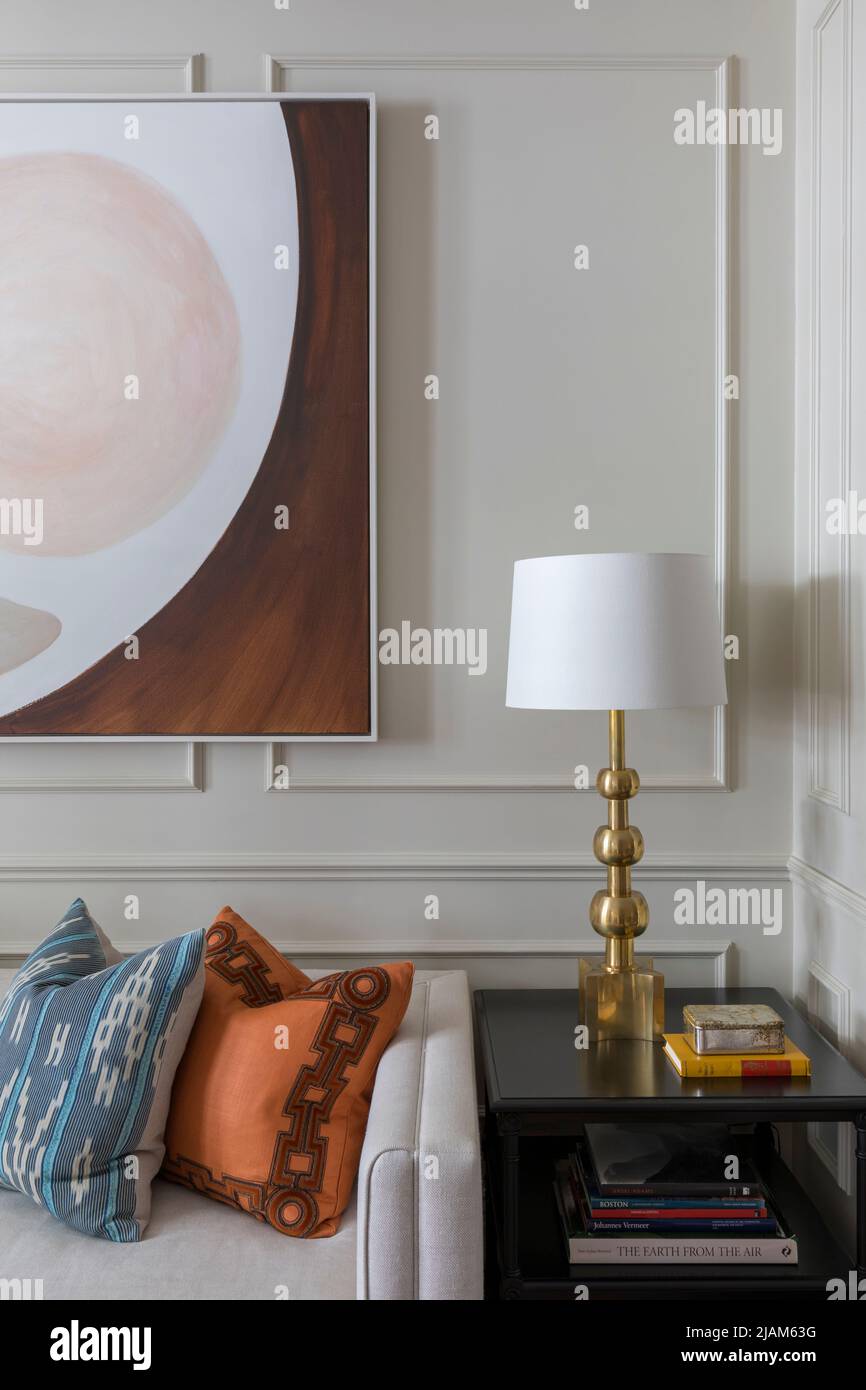 Tavolo laterale con lampada in ottone, opere d'arte moderne e pareti a pannelli Foto Stock