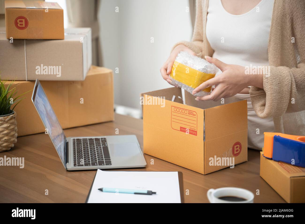 Donna asiatica imballaggio in scatole per lavorare a casa piccoli proprietari di affari o Startup imprenditori di piccola impresa che lavorano sulle scatole di trasporto in linea di vendita. Foto Stock