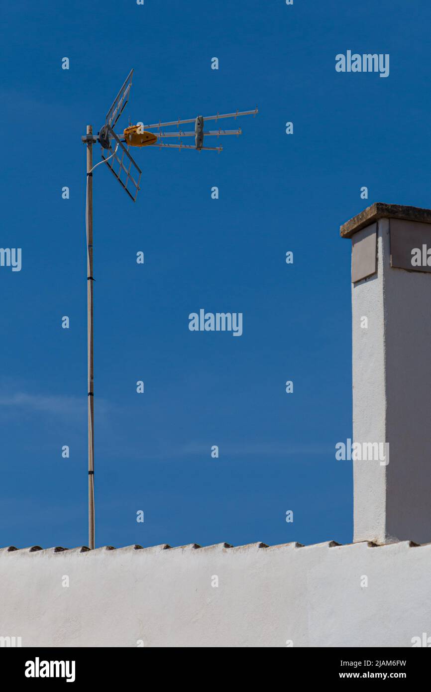 antenna televisiva su un tetto di fronte a un cielo blu Foto Stock