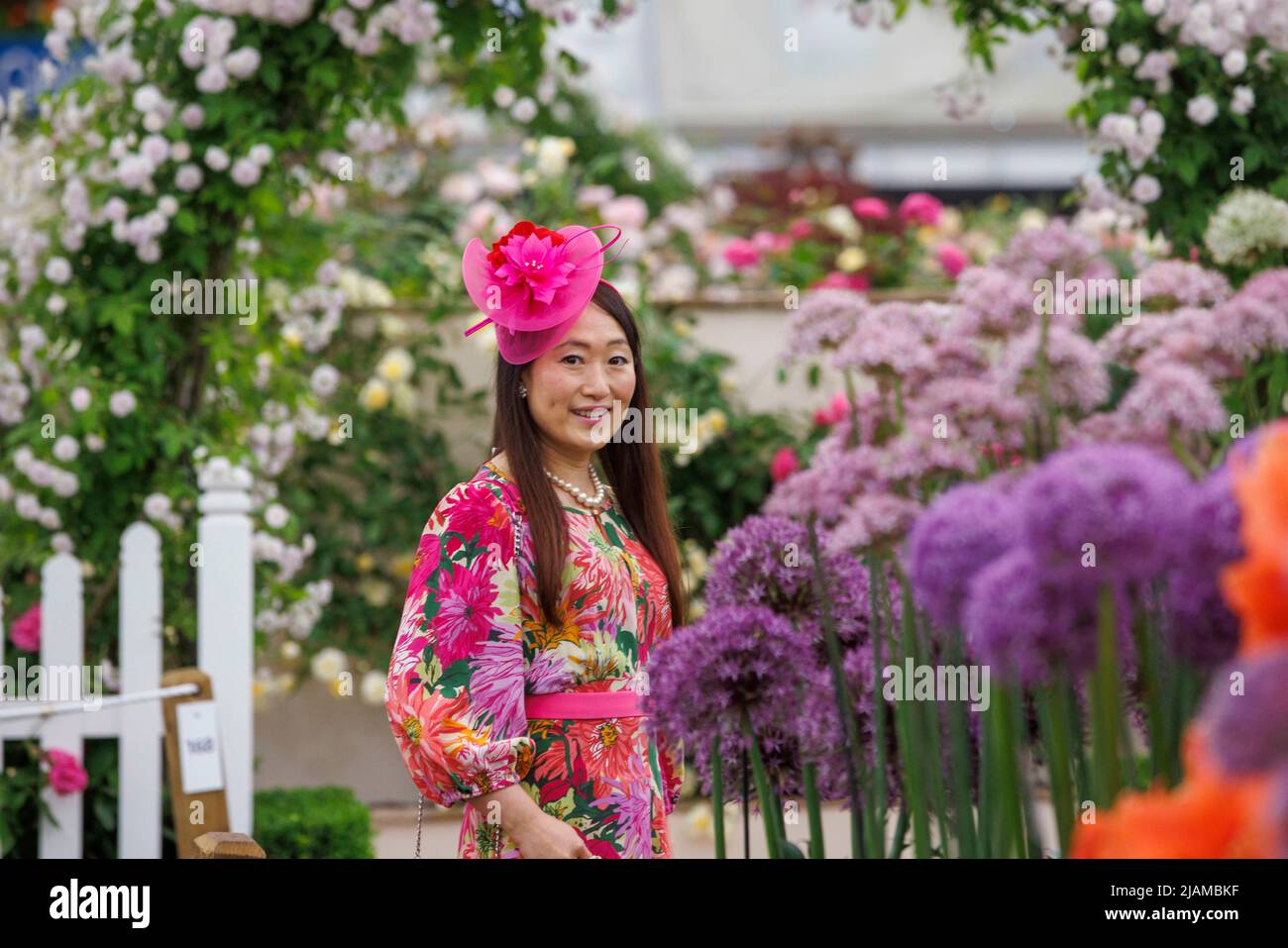 Una signora alla moda con un cappello rosa visita il RHS Chelsea Flower Show, tra gli Aliums e le rose. Foto Stock