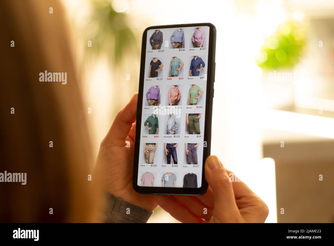 Acquisto online di abiti tramite smartphone. Applicazione sullo schermo di un telefono cellulare nelle mani di una donna. E-commerce. Foto Stock