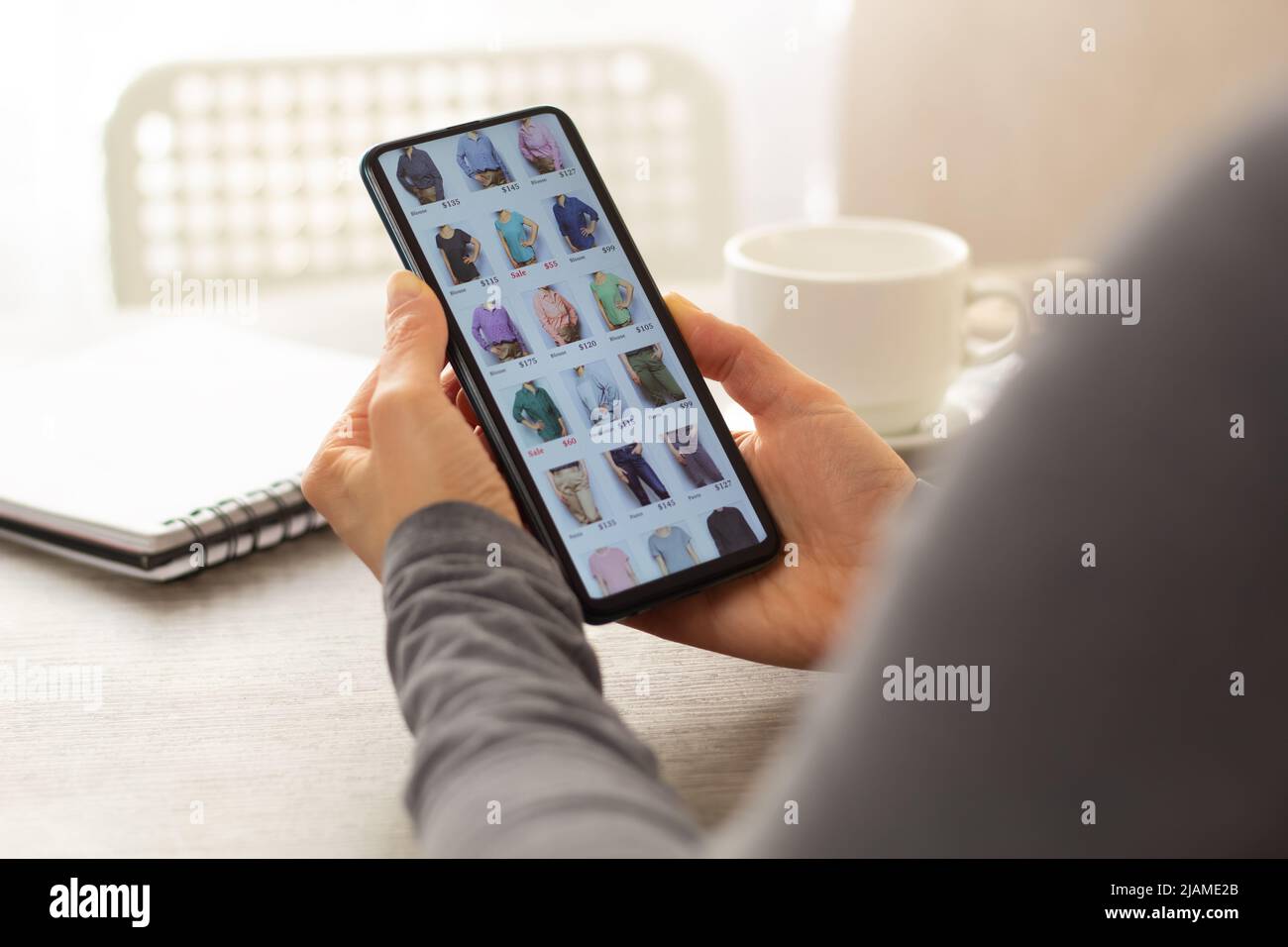 Acquisto online di abiti tramite smartphone. Applicazione sullo schermo di un telefono cellulare nelle mani di una donna. E-commerce. Foto Stock