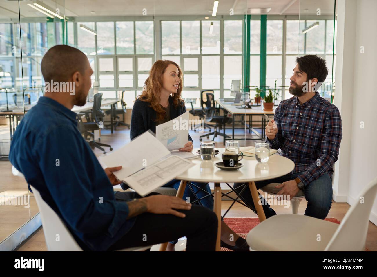Giovani uomini d'affari che parlano durante una riunione casuale in un ufficio Foto Stock