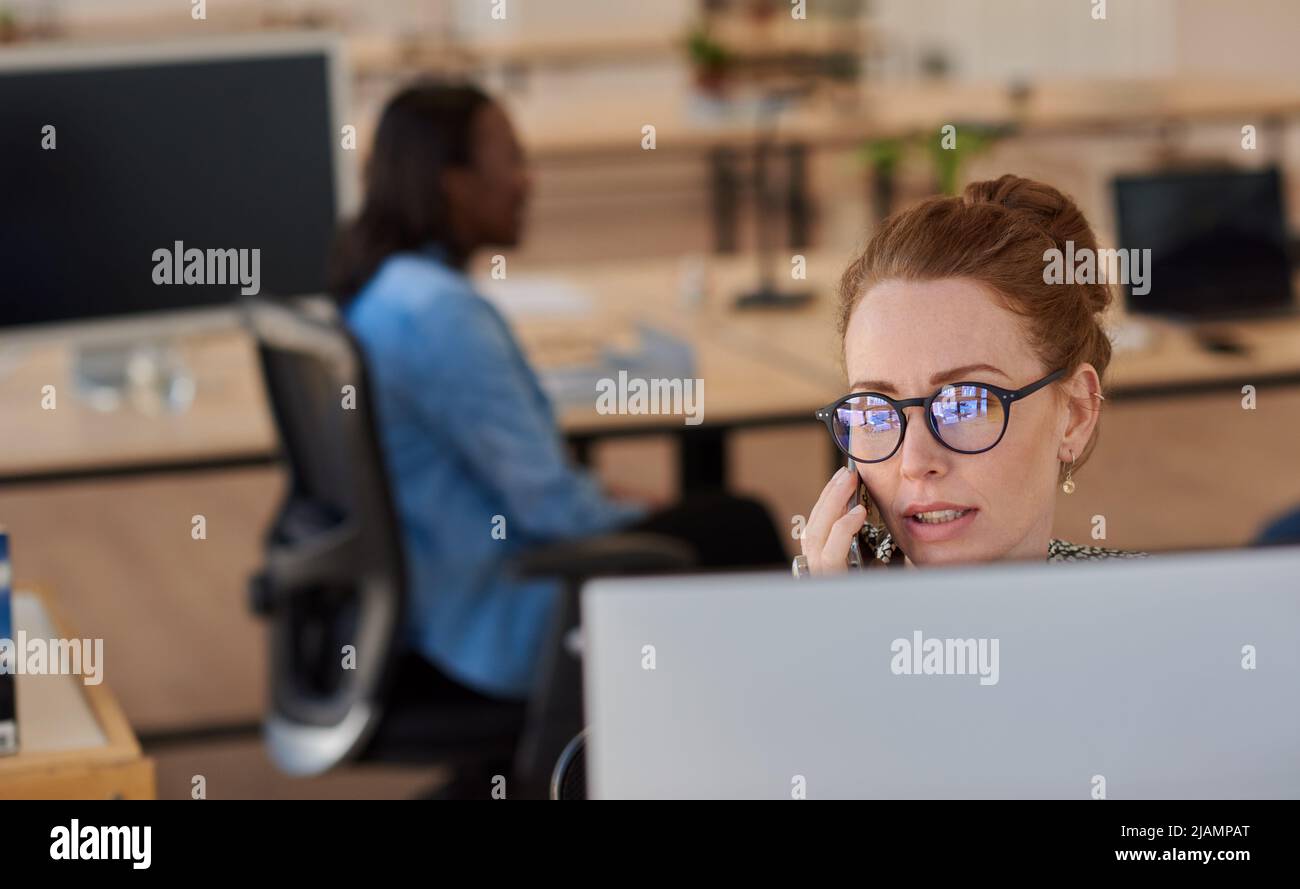 Donna d'affari che lavora al telefono alla sua scrivania d'ufficio Foto Stock